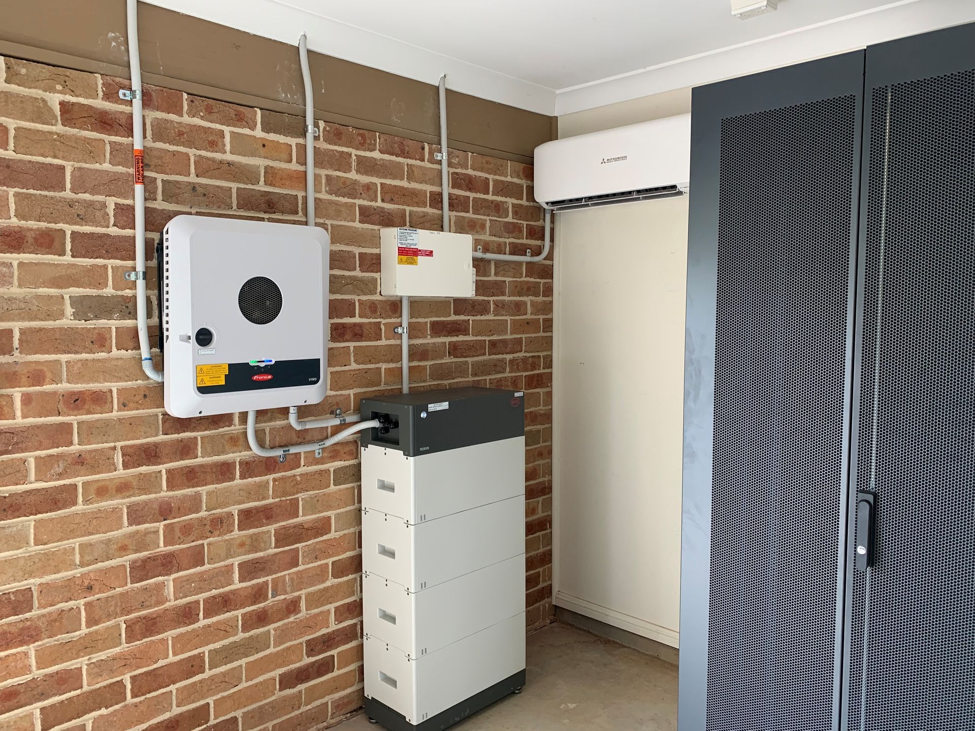 Utility room with brick wall, electrical equipment, cabinet, and a tall storage unit
