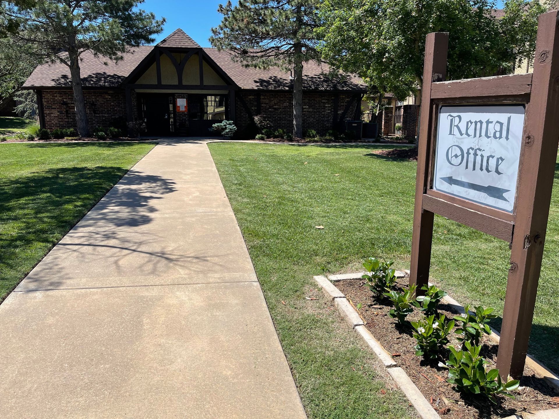 Rental office building with a sign and sidewalk.