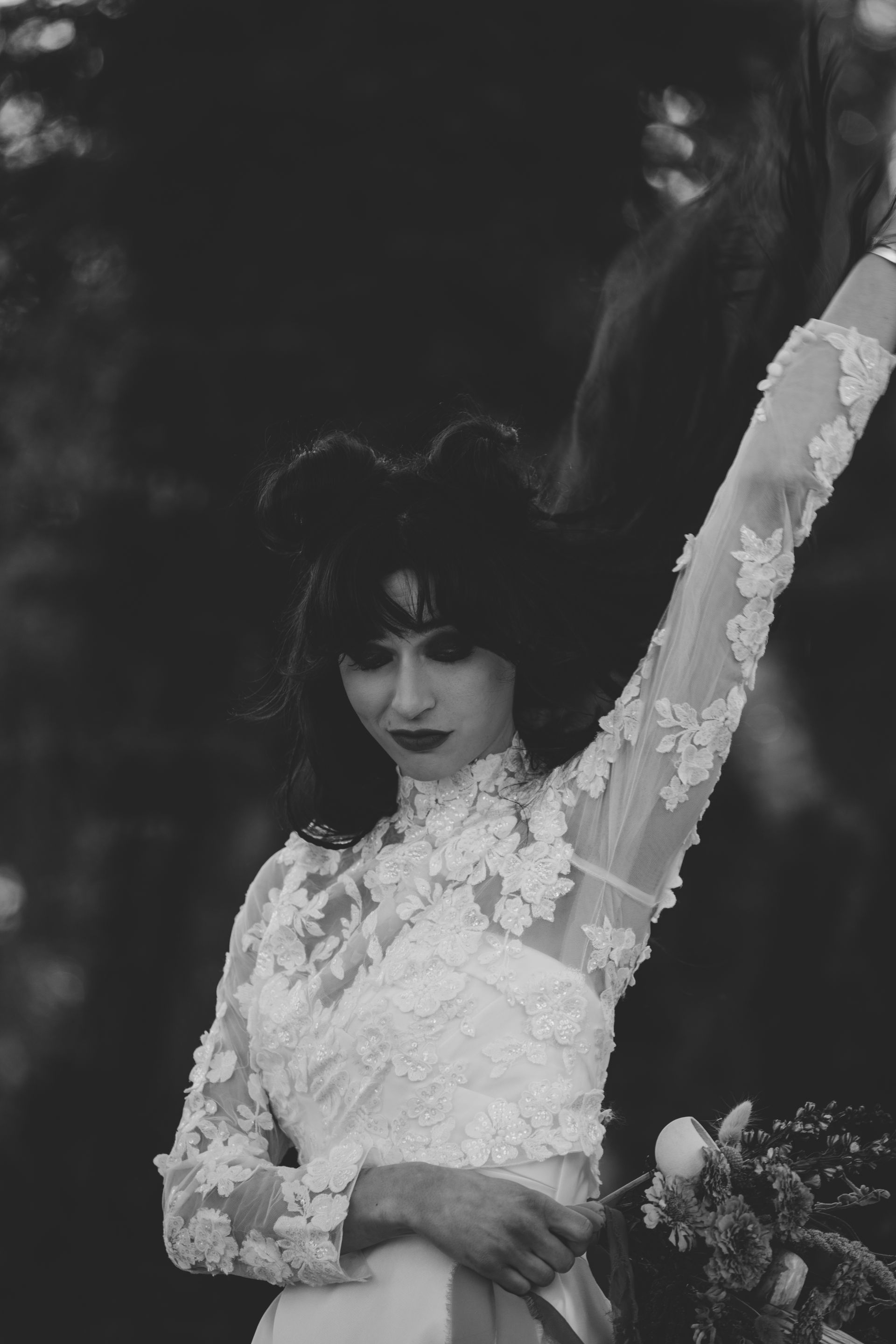 A woman in a white wedding dress is standing in front of a mountain.