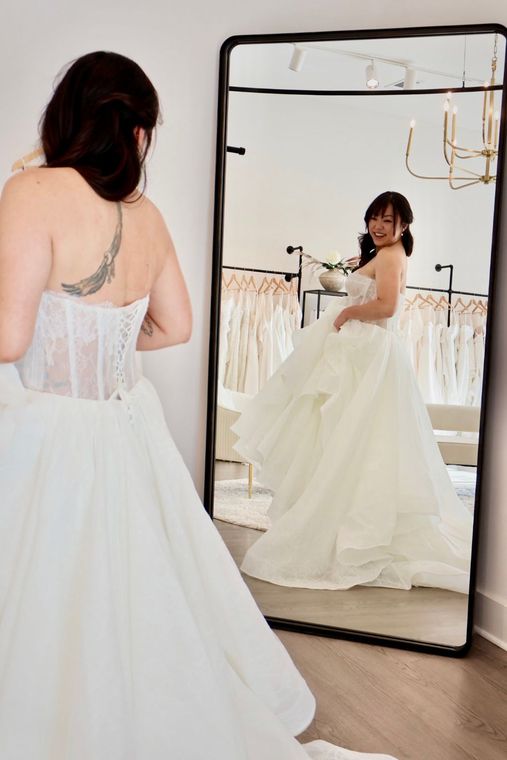A woman is trying on a wedding dress in a bridal shop.