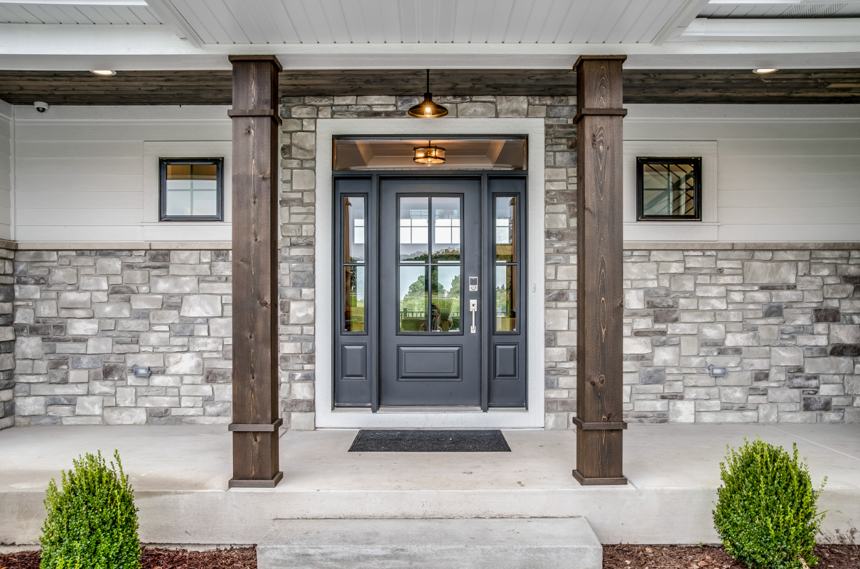 Front entrance with gray stone facade, dark door, and wooden columns.