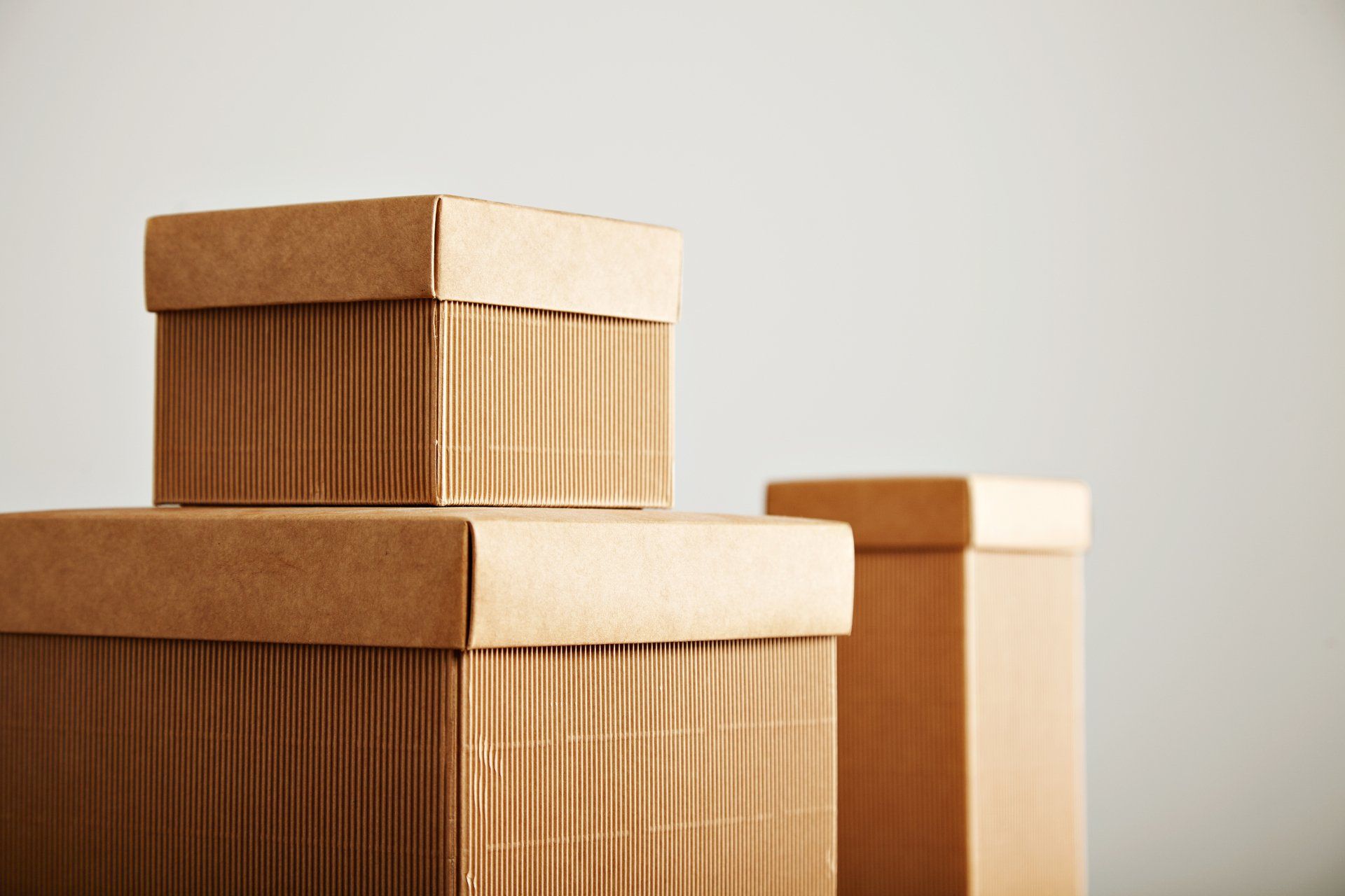 Tres cajas de cartón corrugado beige similares con tapas de diferentes formas y tamaños aislados en blanco Tres cajas de cartón corrugado beige similares con tapas de diferentes formas y tamaños aislados en blanco