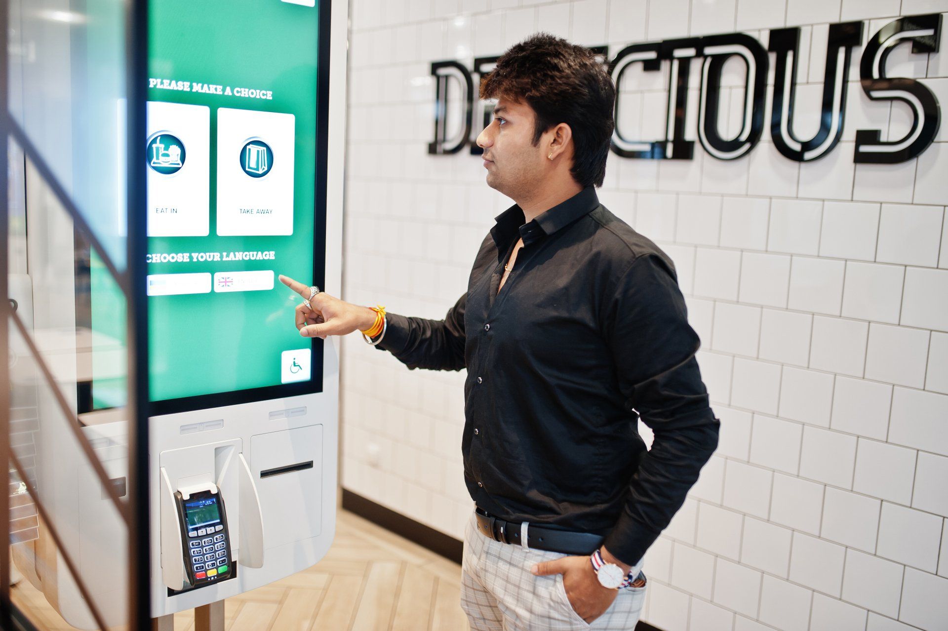El cliente indio en la tienda realiza pedidos y paga a través del quiosco de piso de pago automático El cliente indio en la tienda realiza pedidos y paga a través del quiosco de piso de pago automático