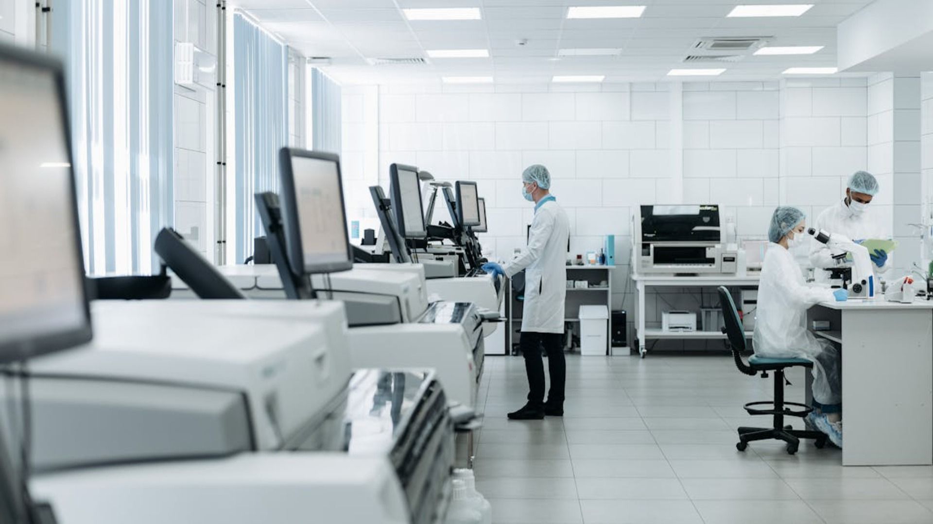 Laboratorio con investigadores con batas y equipo de protección trabajando con equipos.