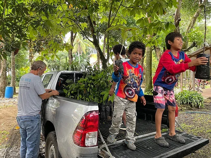 Men and children unloading plants from a pickup truck.