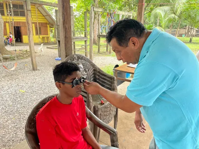 Vision screening during a medical outreach as an adult administers an eye exam for a child