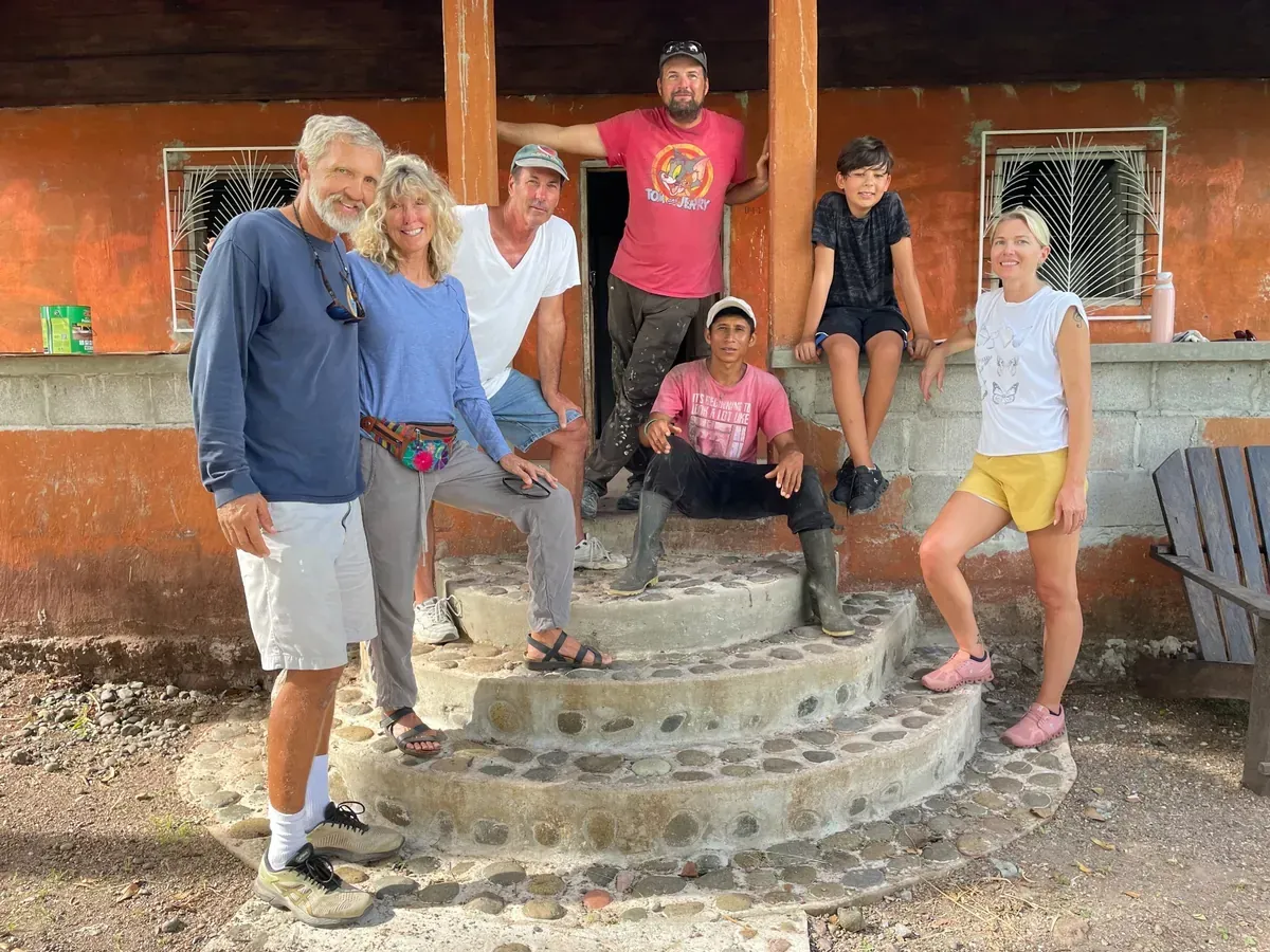 Group of volunteers pose on stone steps of an orange missino house