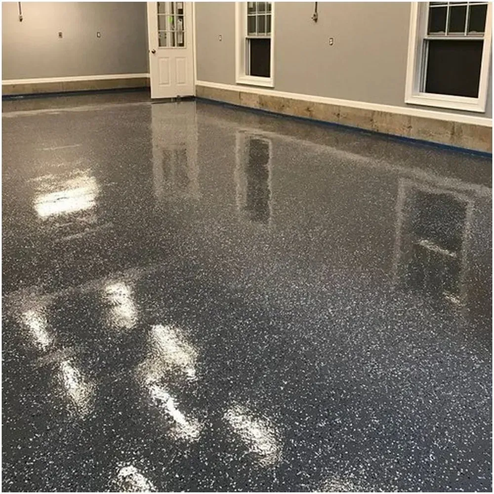 Epoxy-coated garage floor with gray and white flecks reflecting light. Windows and door in the background.