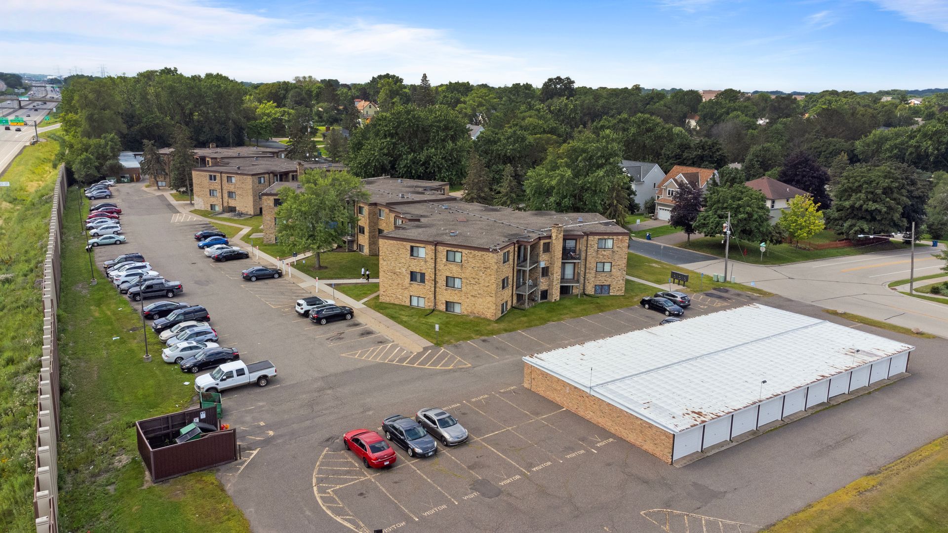 An aerial view of a parking lot with cars parked in front of a building.