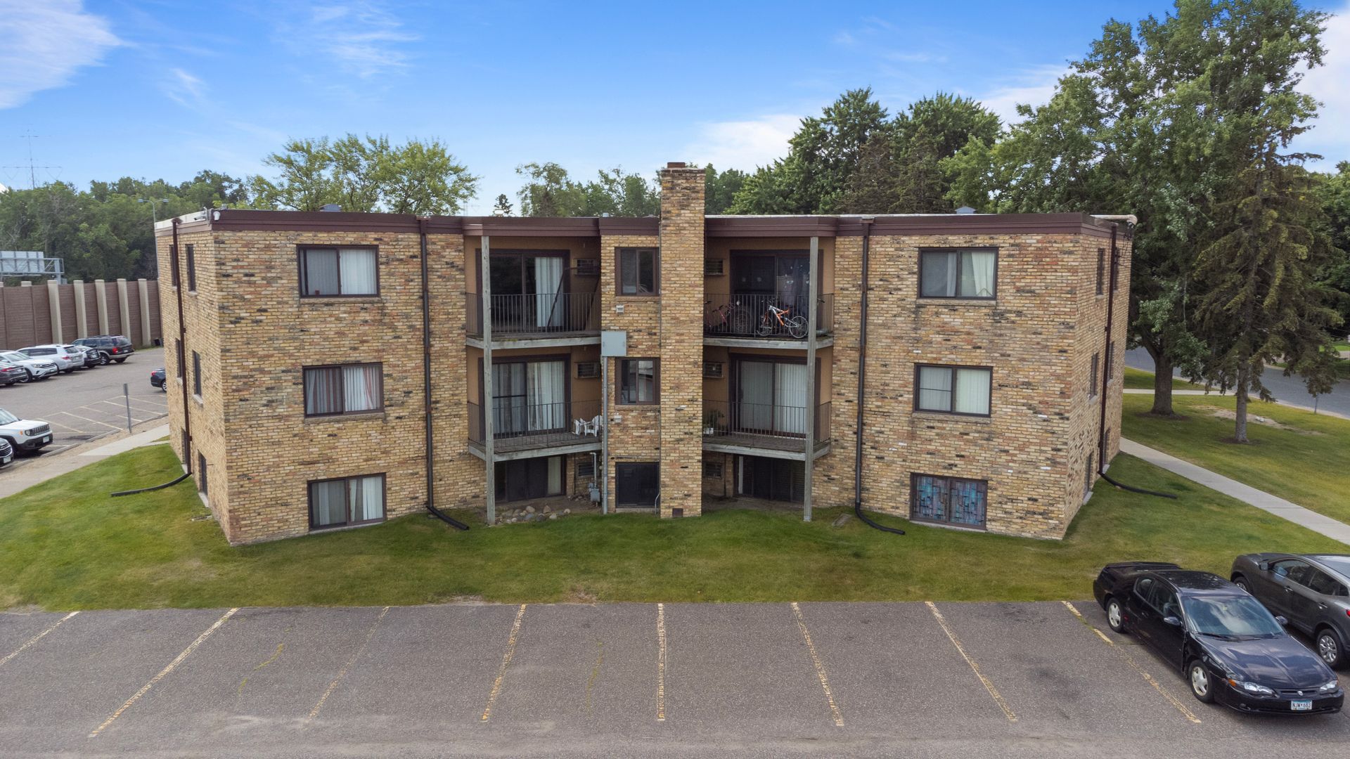 An aerial view of a brick apartment building with cars parked in front of it.
