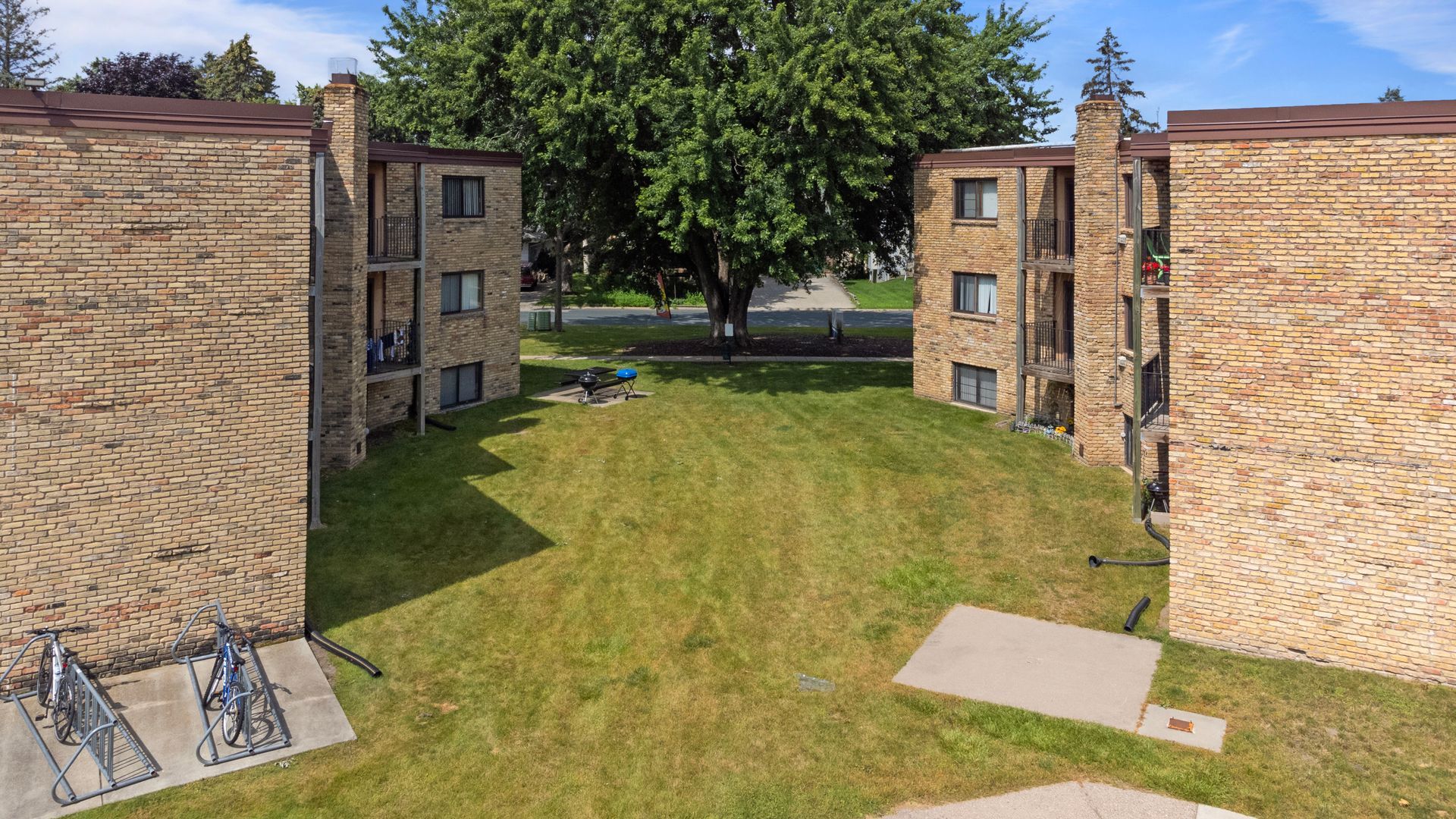 An aerial view of a brick apartment building with bikes parked in front of it.