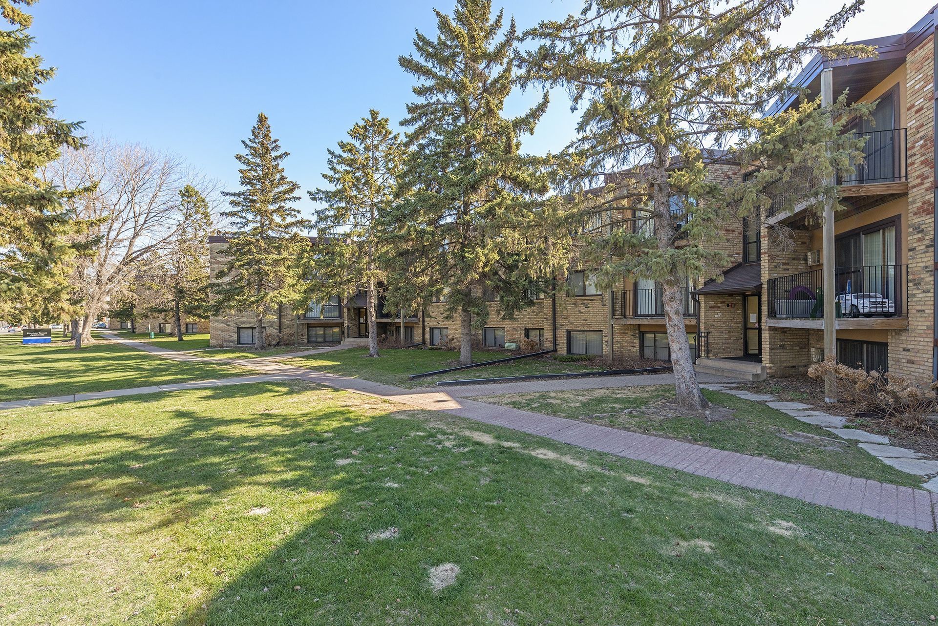 A large apartment building with a lush green lawn in front of it.