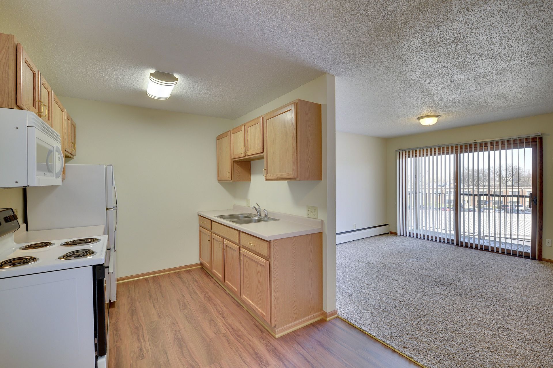 A kitchen with a stove , refrigerator , microwave and sink.