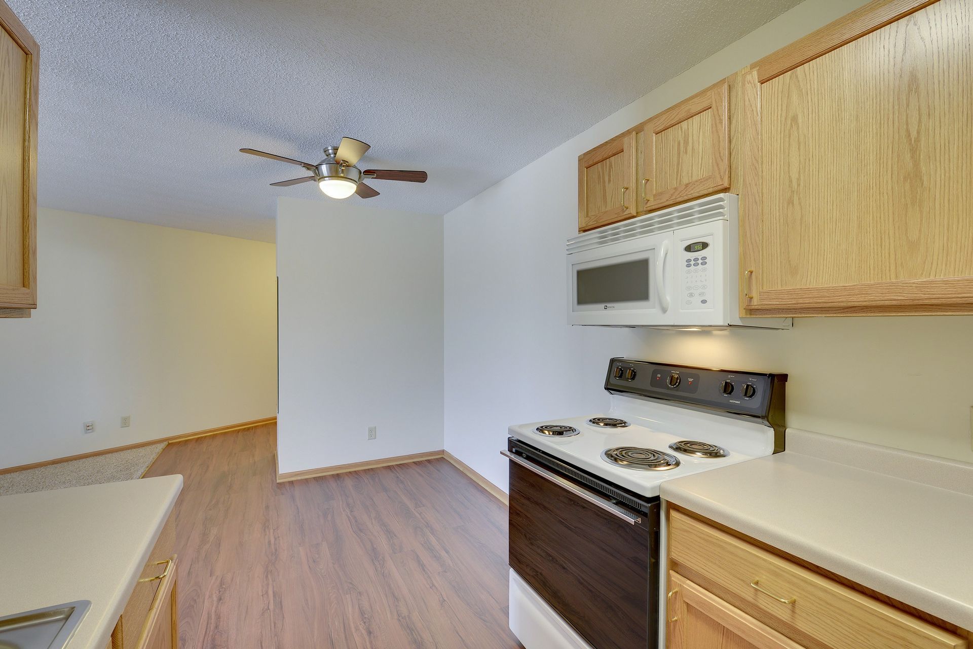 A kitchen with a stove , microwave and ceiling fan