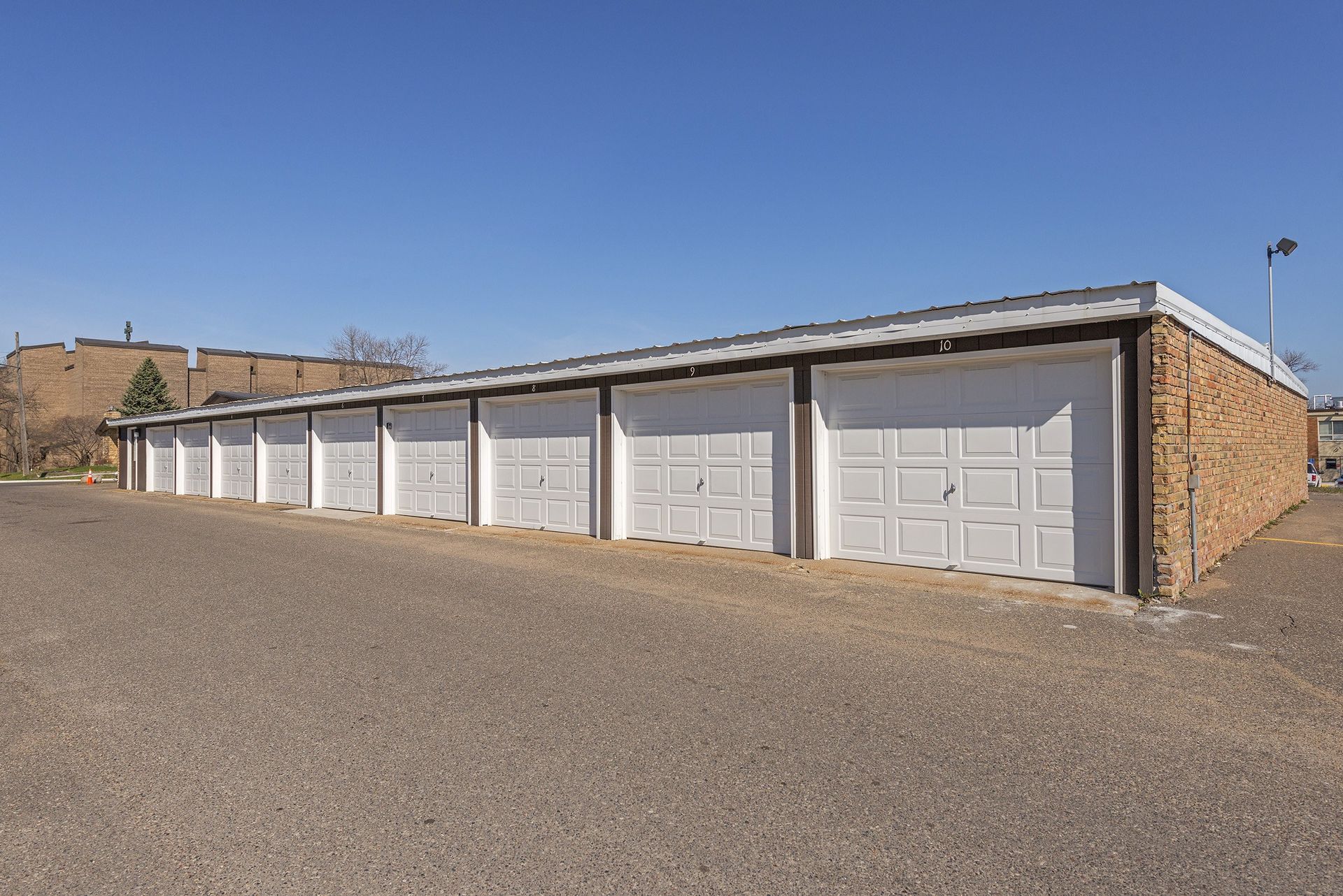 A row of white garage doors are lined up in a parking lot.