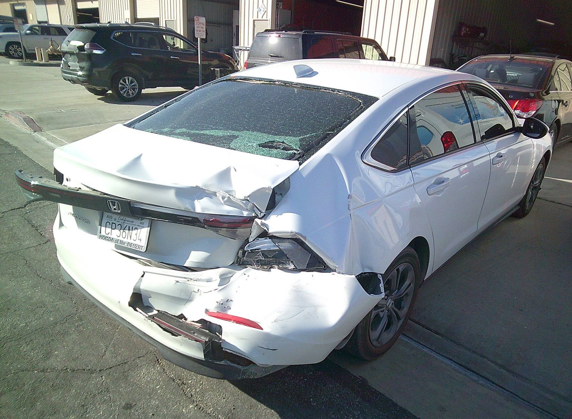 A white car that has been damaged is parked on the side of the road