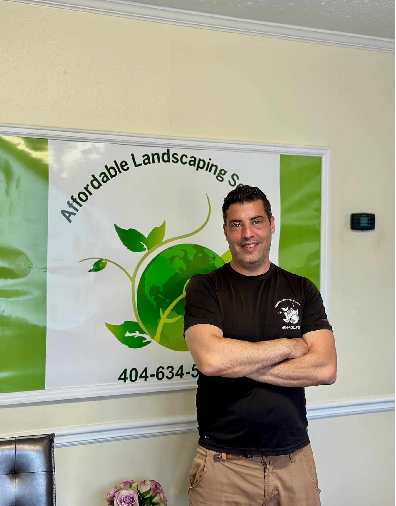 Man standing with arms crossed in front of an Affordable Landscaping Services banner.