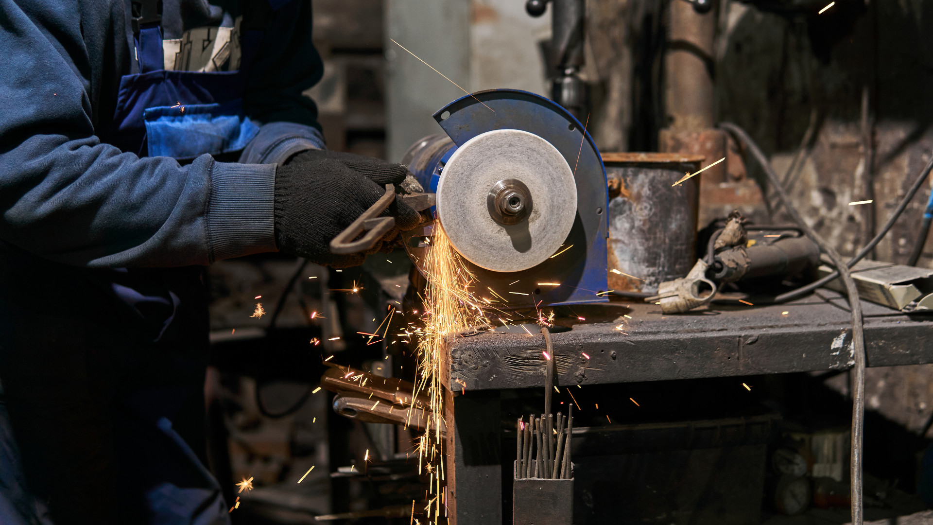 Person grinding metal with sparks flying in a workshop.