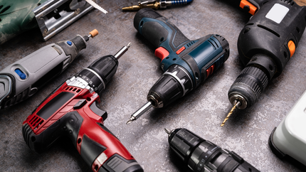 Assortment of power drills, including a rotary tool, against a mottled gray background.