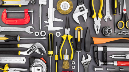 Assorted hand tools arranged on a gray surface, including wrenches, pliers, and a hammer.
