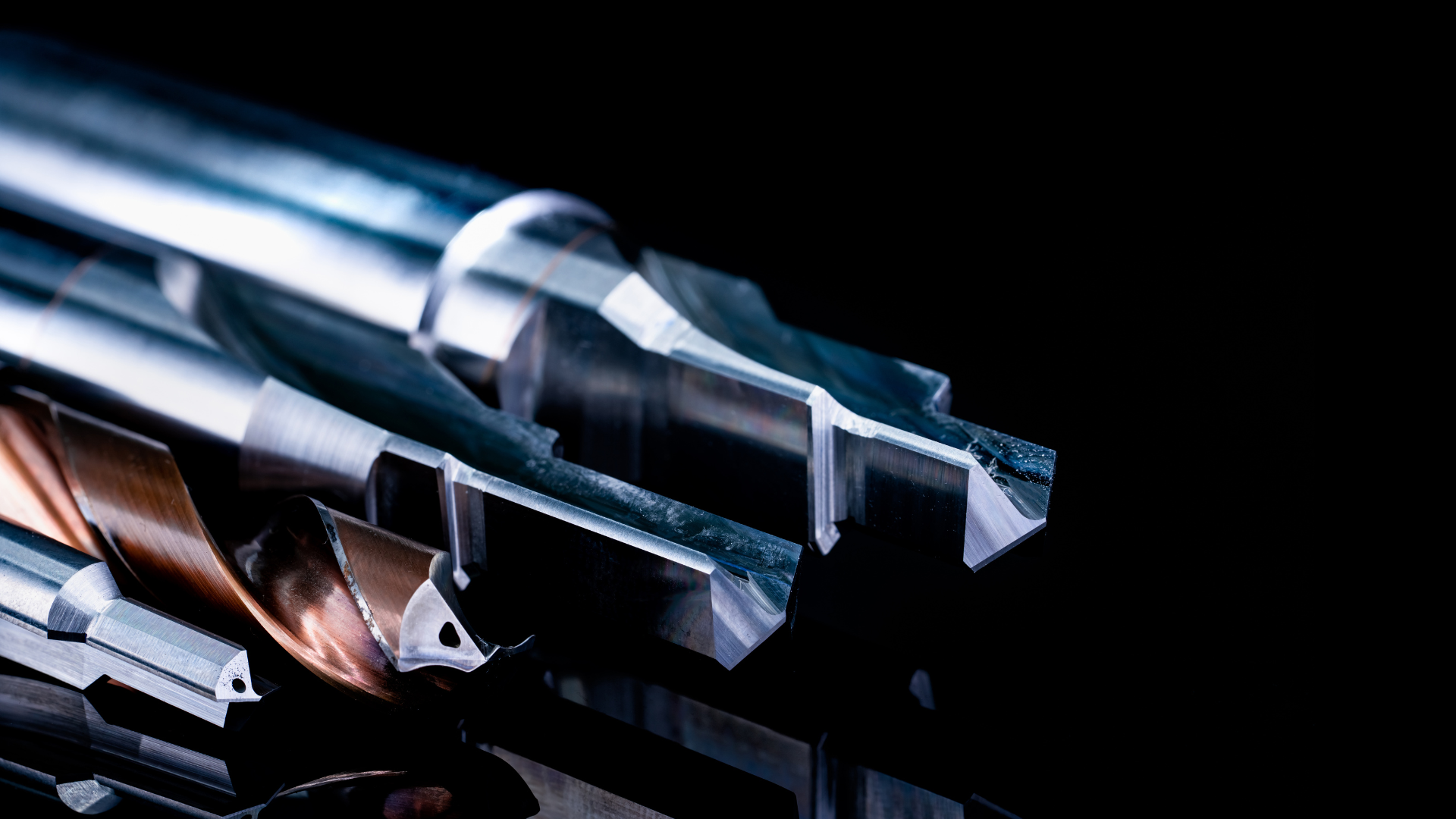 Metal cutting tools against a black background, with sharp edges and a copper-colored element.