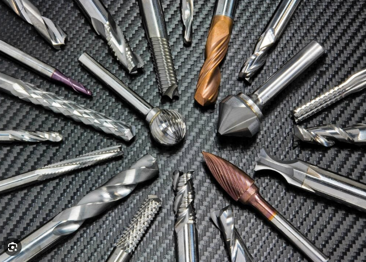 Cutting tools arranged on a black carbon fiber background, showing various drill bits and milling cutters.