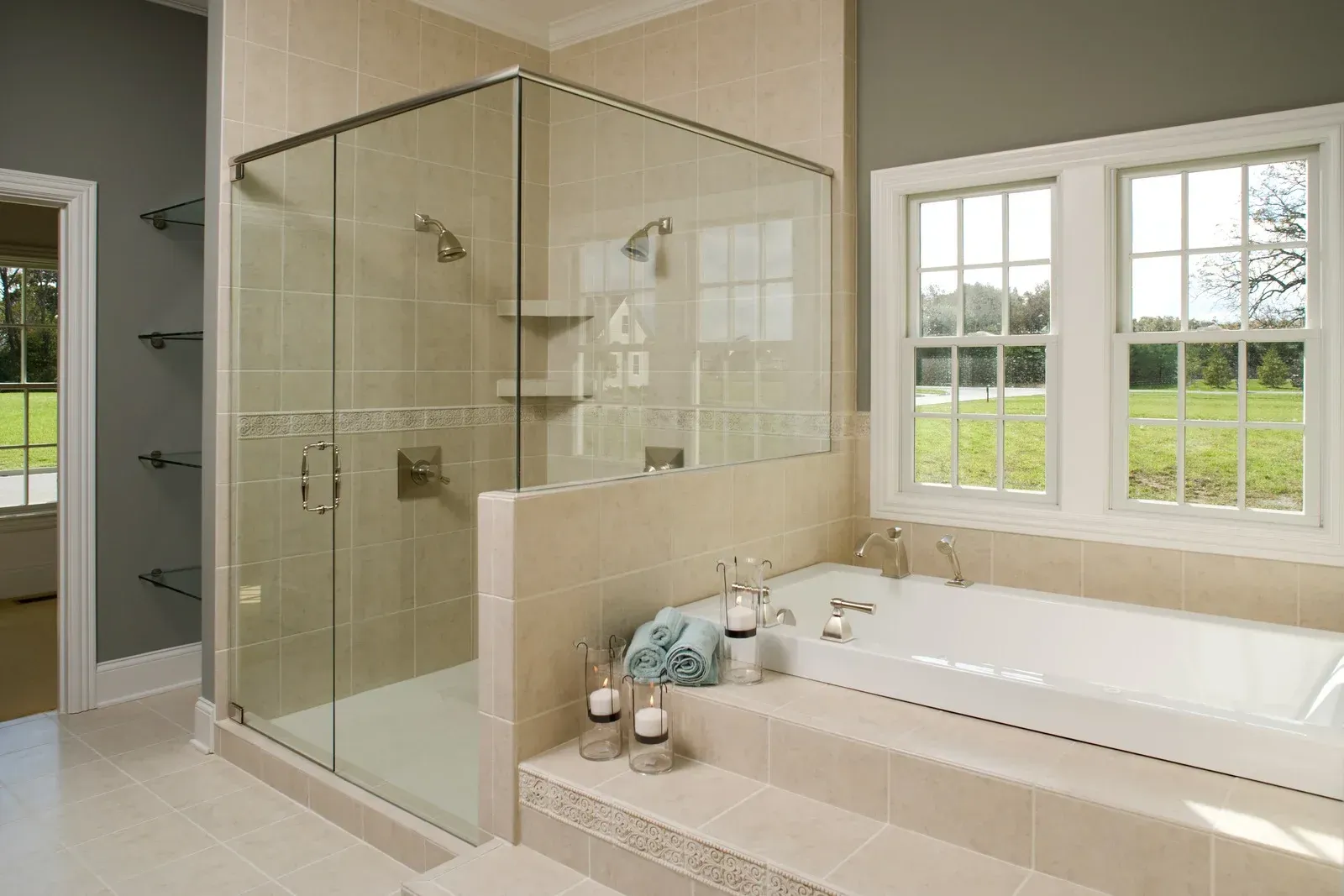 Modern bathroom with glass shower, beige tile, and a soaking tub by a window