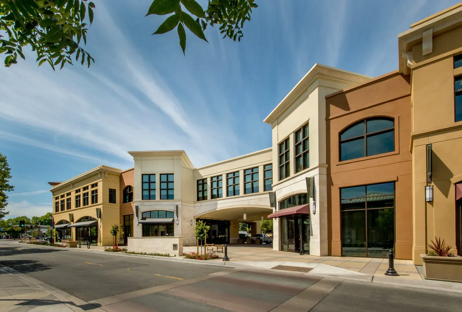 Row of modern storefronts on a sunny street with trees and blue sky
