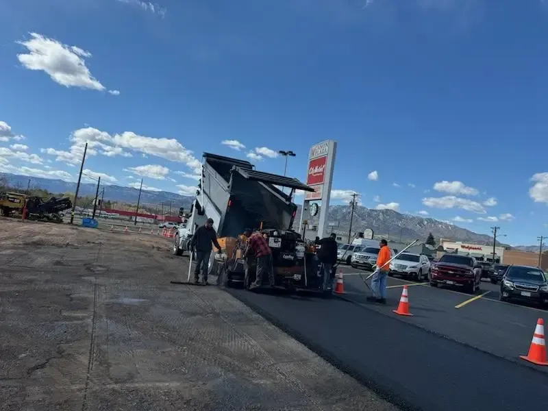 A group of people are standing around a dump truck in a parking lot.