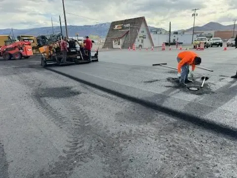 A group of people are working on a road in a parking lot.