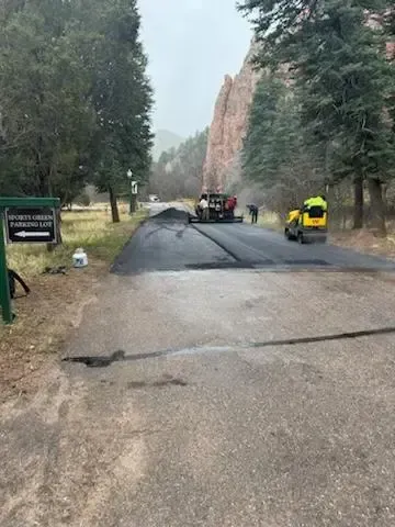 A jeep is driving down a road next to a sign.