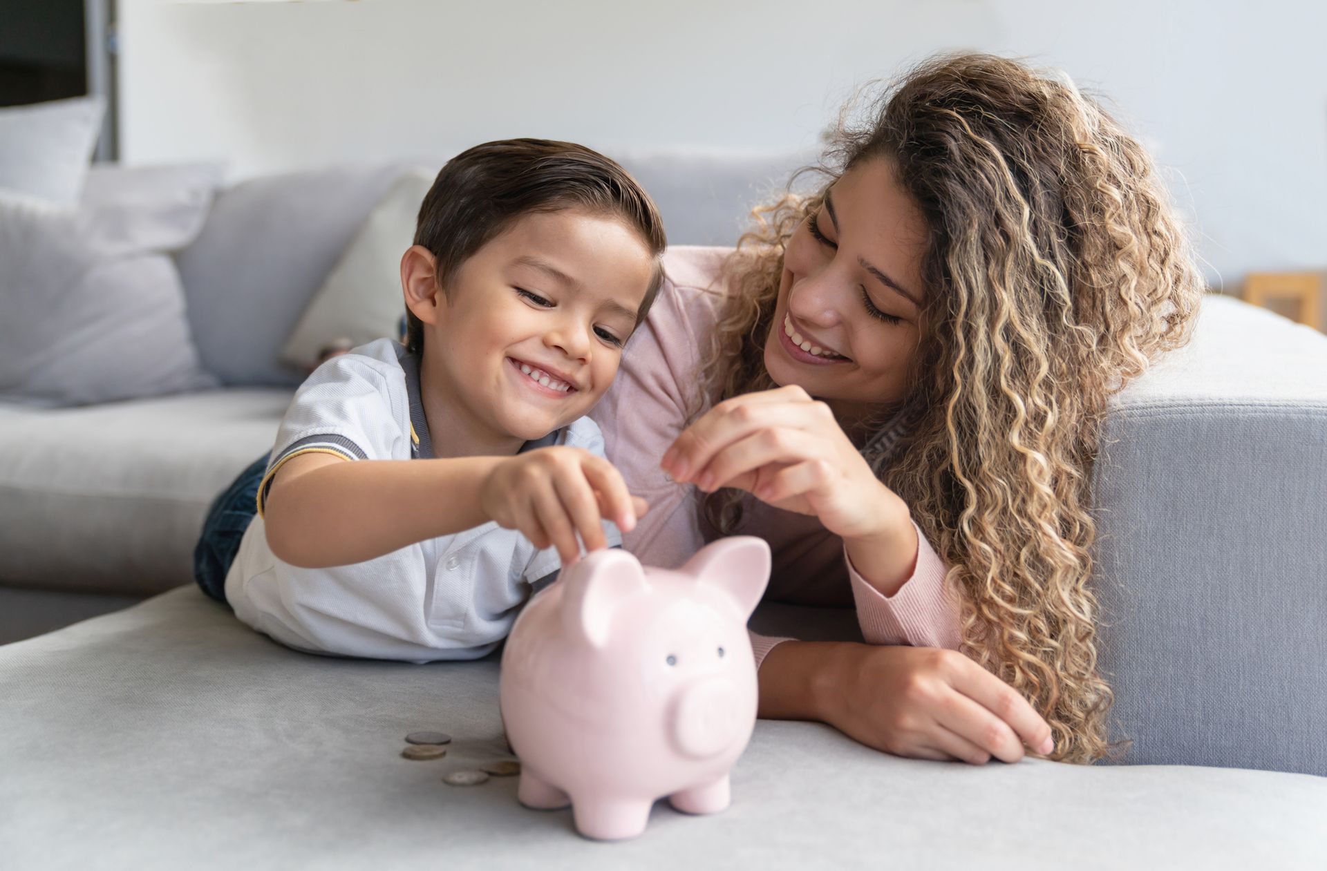 A woman and a child are putting coins into a piggy bank.