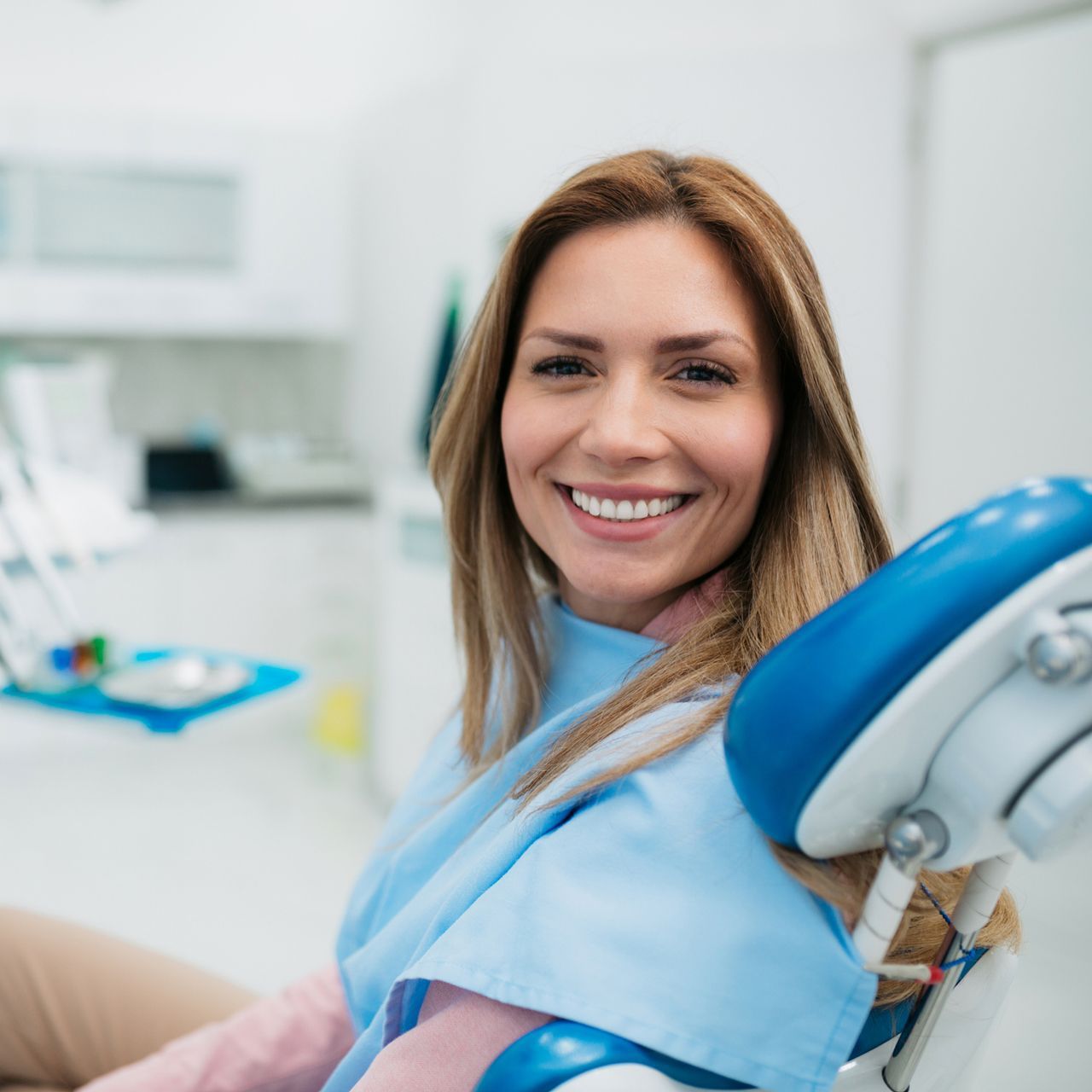 A woman is smiling while sitting in a dental chair