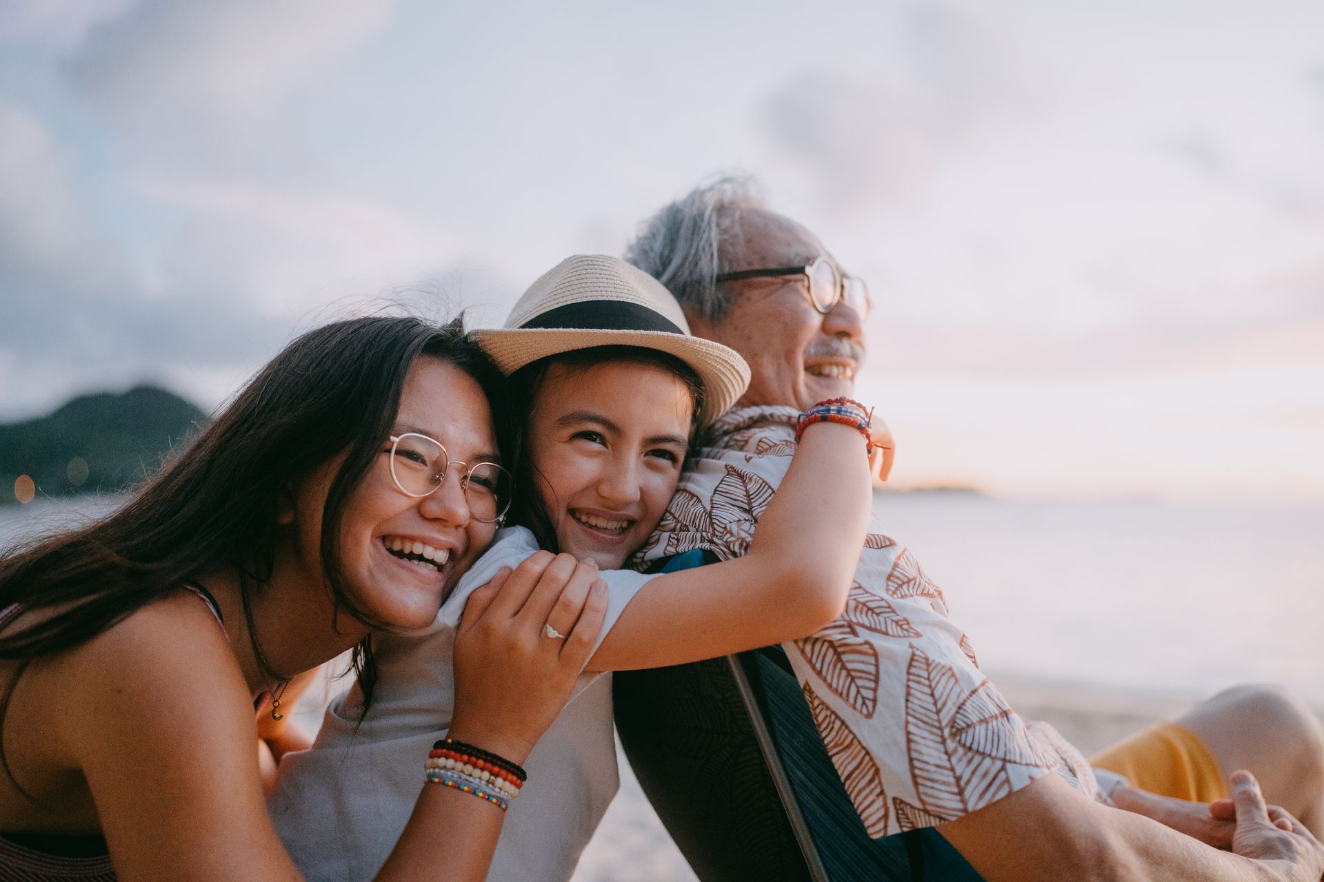 A family is sitting on the beach and hugging each other.