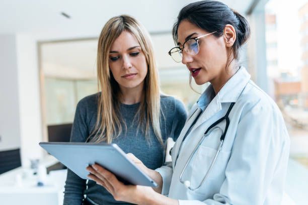 A doctor and a patient are looking at a tablet together.