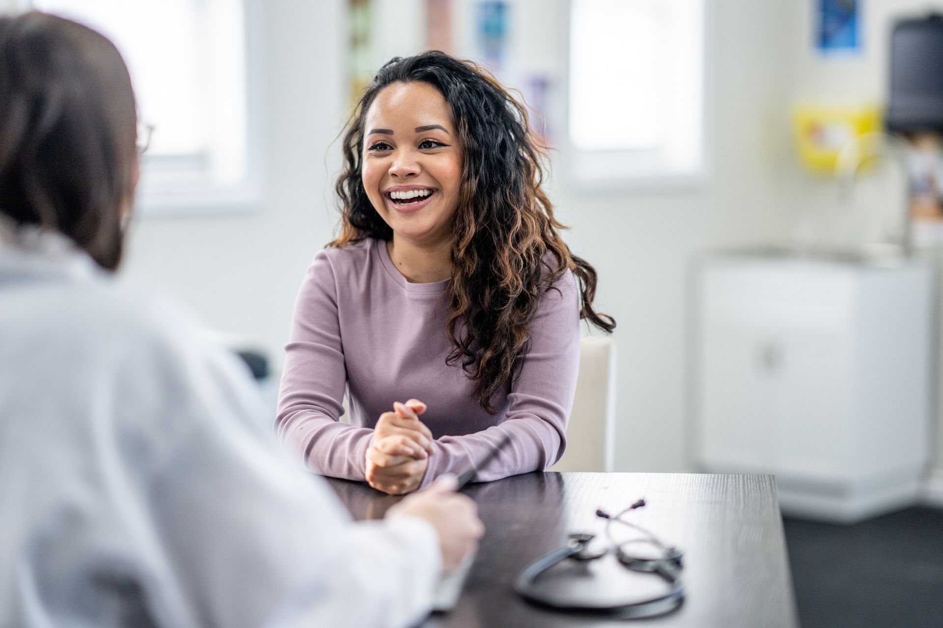 A woman is sitting at a table talking to a doctor.