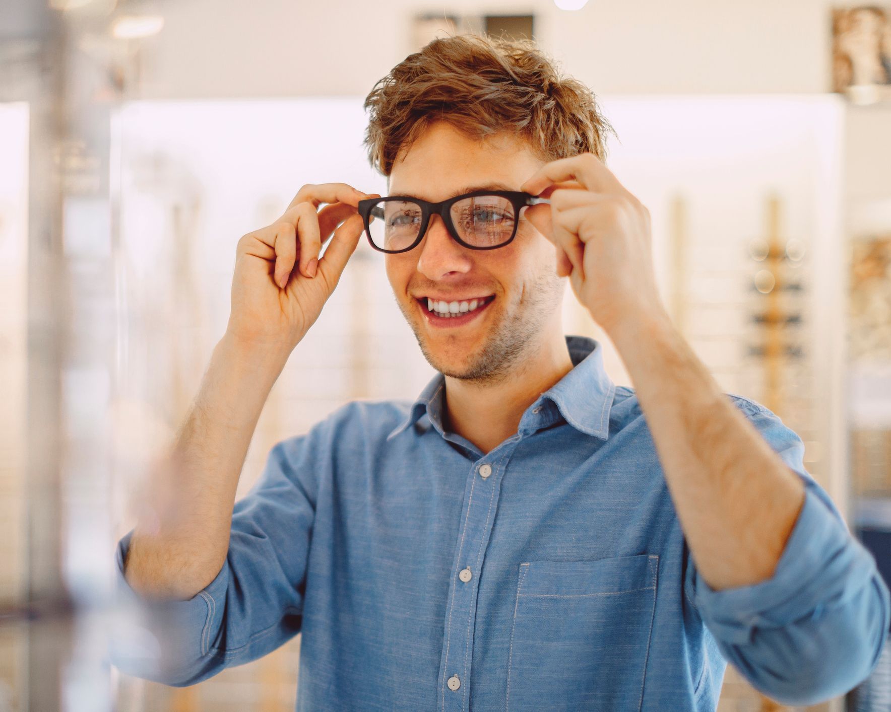 A man is trying on glasses in an optical shop.