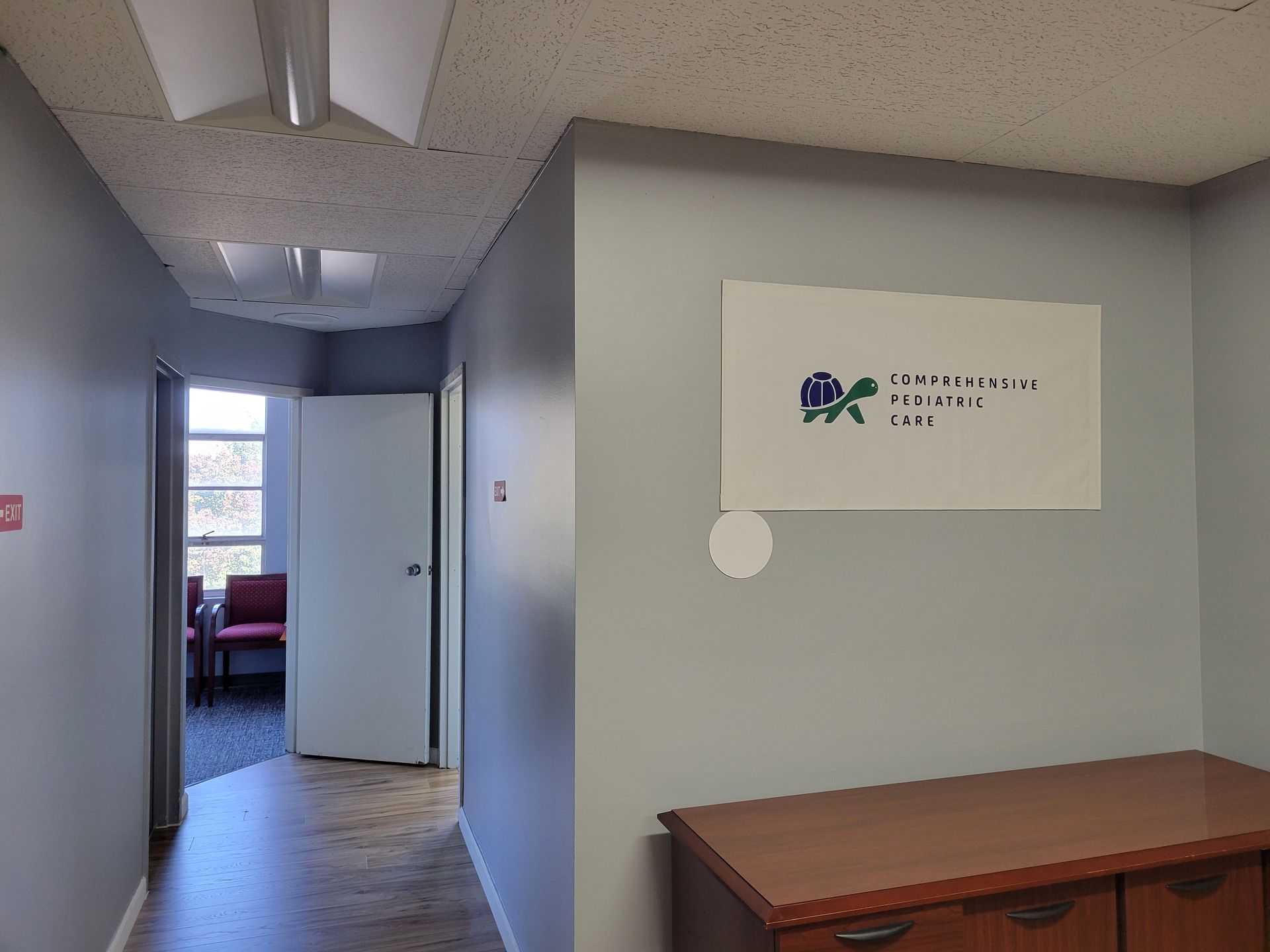 A hallway with a sign on the wall that says Comprehensive Pediatric Care on it.