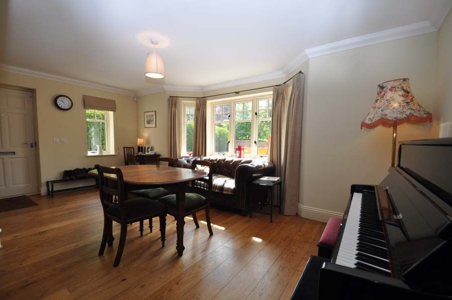 Living room with piano, sofa, dining table, and large window.