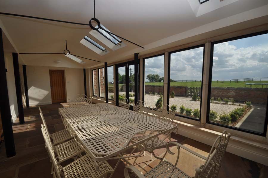 Dining room with white table and chairs, large windows with outdoor view, and skylights.