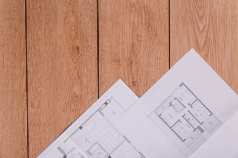 Blueprints on a wooden table, likely for architectural planning.