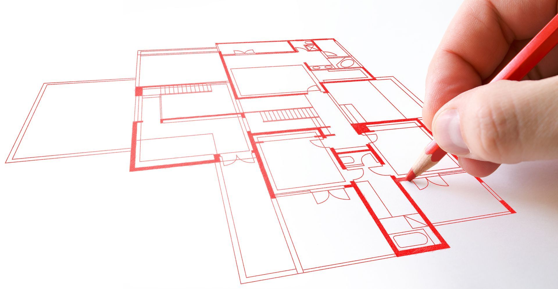 Hand drawing a red architectural floor plan on white paper.