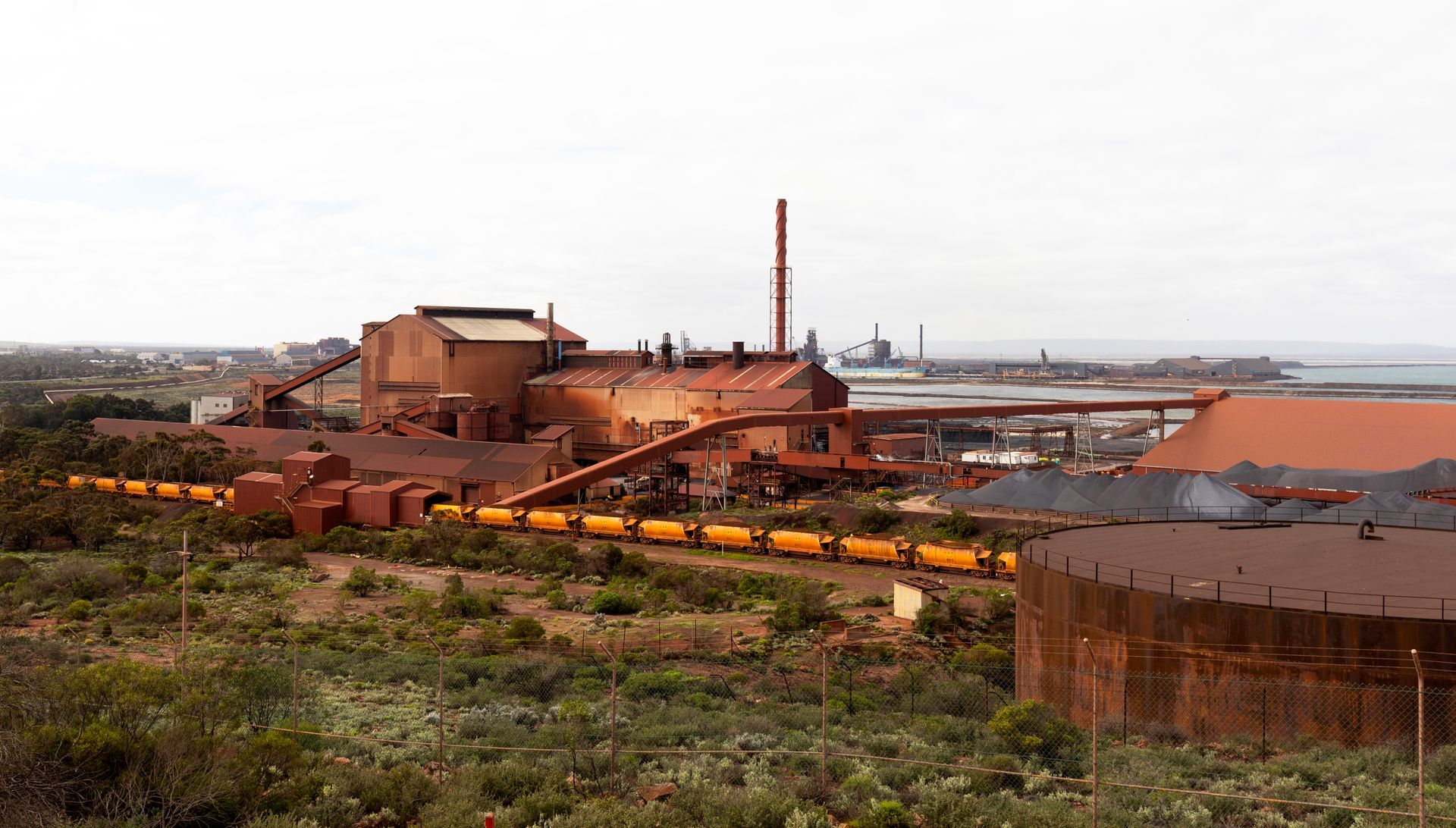 Landscape image with coal train, coal storage and shipping port in distance