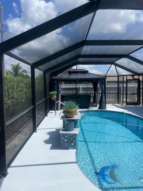 A screened in swimming pool with a gazebo in the background.