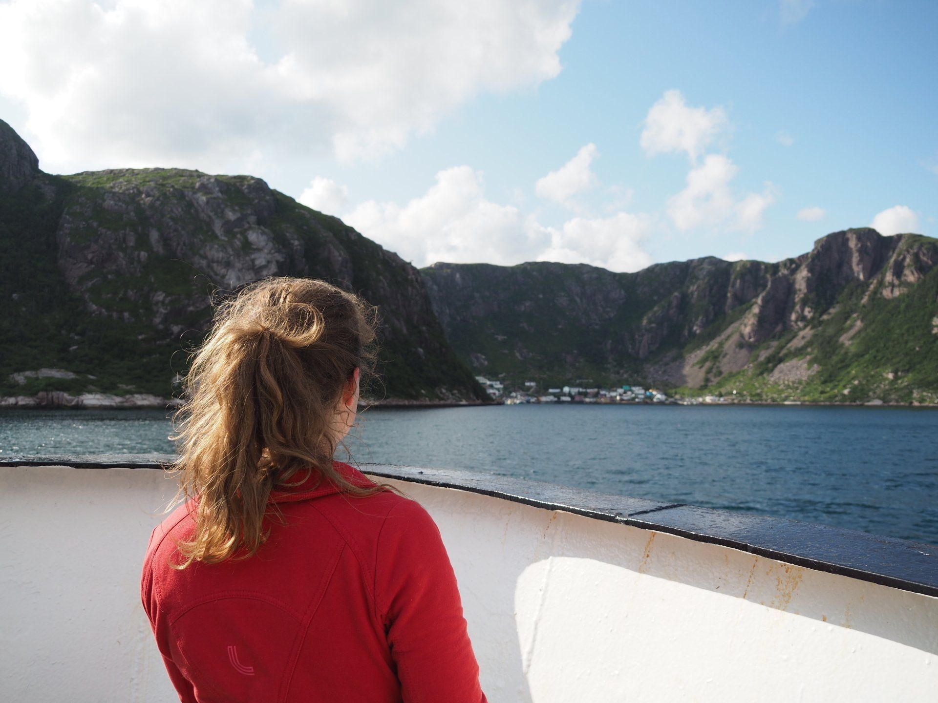 Une jeune femme, vue de dos, regarde le fjord près de Francois depuis le pont du bateau.