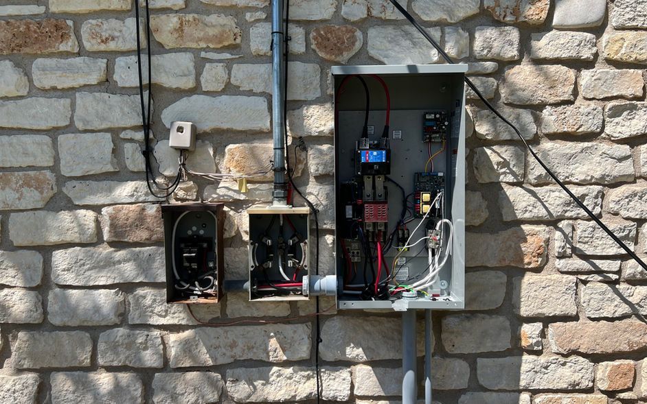 There are two electrical boxes on the side of a brick building.