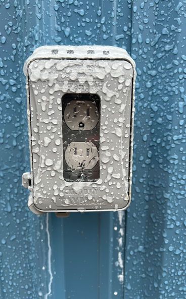 A close up of a waterproof electrical outlet on a blue wall.