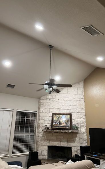 A living room with a fireplace and a ceiling fan.