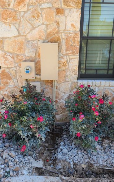 A house with a box on the side of it and flowers in front of it.