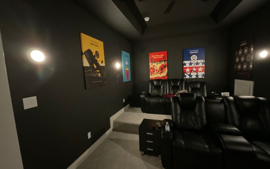 A home theater with black seats and posters on the walls